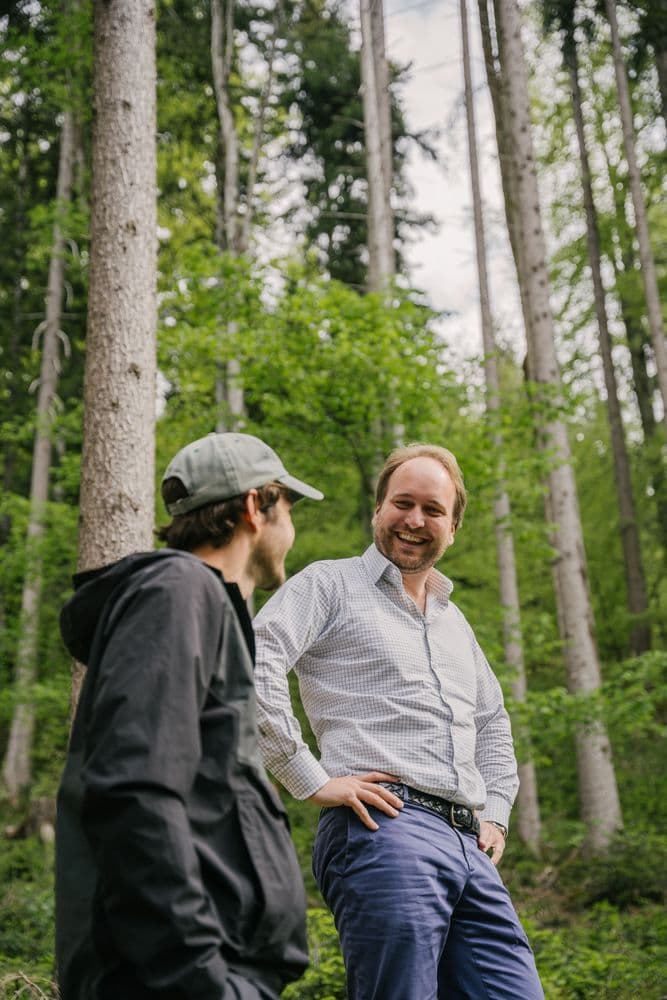 two men in the forest looking at each other 