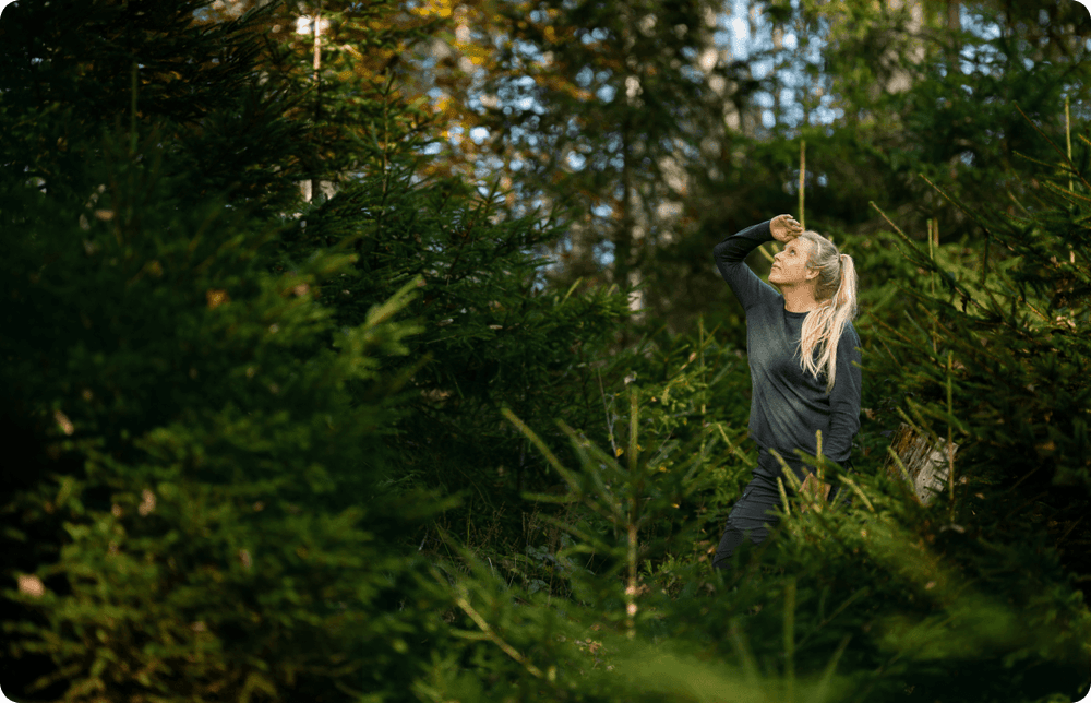 Bild indem eine Frau im Wald steht und nach oben schaut